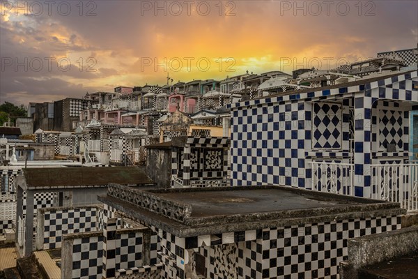 Famous cemetery, many mausoleums or large tombs decorated with tiles, often in black and white. Densely built buildings under a sunset Cimetiere de Morne-a-l'eau, Grand Terre, Guadeloupe, Caribbean, North America