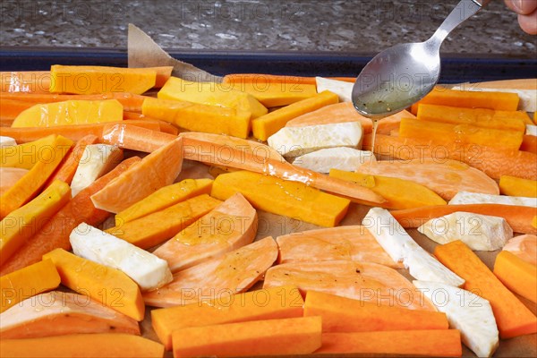 South German cuisine, butternut squash, butternut squash, pumpkin drizzled with olive oil, vegetables cut on baking tray, preparation of oven vegetables, pumpkin, fruit vegetables, fruit, carrots, celery, healthy cooking, vegetarian, vegan, autumn cuisine, pumpkin dishes, food, studio, man's hand, tablespoon, Germany, Europe