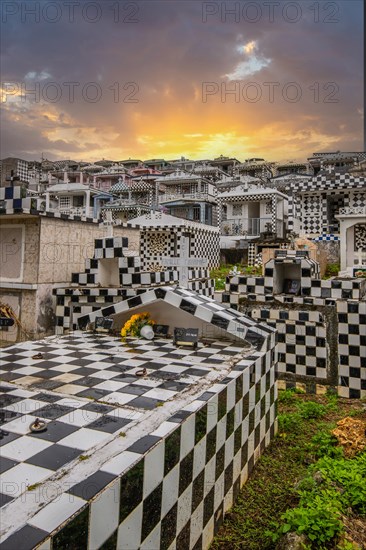 Famous cemetery, many mausoleums or large tombs decorated with tiles, often in black and white. Densely built buildings under a sunset Cimetiere de Morne-a-l'eau, Grand Terre, Guadeloupe, Caribbean, North America