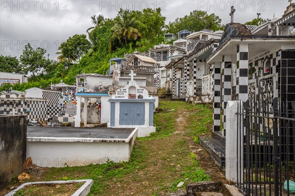 Famous cemetery, many mausoleums or large tombs decorated with tiles, often in black and white. Densely built buildings under a dramatic cloud cover Cimetiere de Morne-a-l'eau, Grand Terre, Guadeloupe, Caribbean, North America