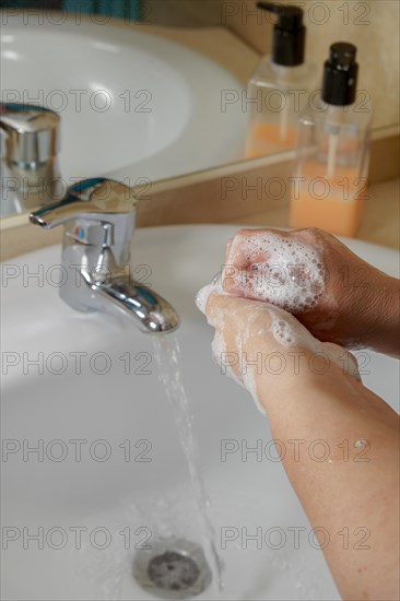 Closeup of a woman washing her hands with liquid soap suds in the bathroom sink. Hand hygiene from bacteria. Foam foams in women's hands