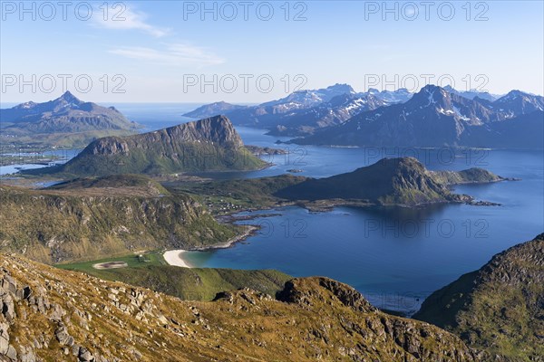 Landscape with sea and mountains. Descent from Himmeltindan mountain. View of the light-coloured sandy beach of Vik (Vik Beach) and Vik Bay (Vikbukta) as well as the mountains Offersoykammen and, on the left at the edge, Skottinden. In the background the mountains of Flakstadoya. Early summer. Vestvagoya, Lofoten, Norway, Europe