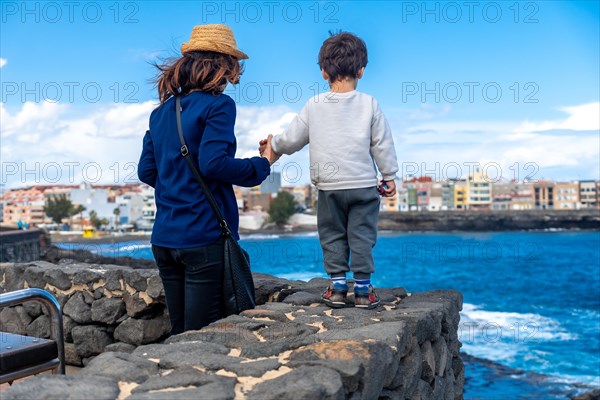 Mother with her son looking at the sea on summer vacation, enjoying family
