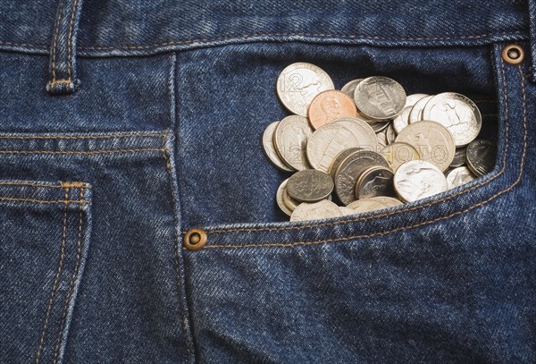 Close-up of US 5, 10, 25 cent coins bulging out of the front pocket of a pair of blue denim jeans, Studio Composition, Quebec, Canada, North America