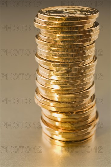 Close-up of stack of gold colored Canadian one dollar coins on silver background, Studio Composition, Quebec, Canada, North America
