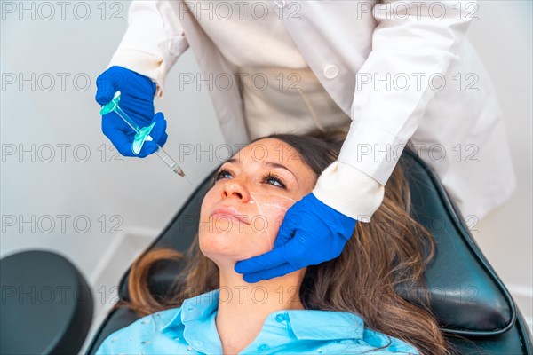 Elevated view of an unrecognizable female cosmetologist administering hyaluronic acid to the face of a woman in a beautician clinic