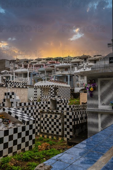 Famous cemetery, many mausoleums or large tombs decorated with tiles, often in black and white. Densely built buildings under a sunset Cimetiere de Morne-a-l'eau, Grand Terre, Guadeloupe, Caribbean, North America