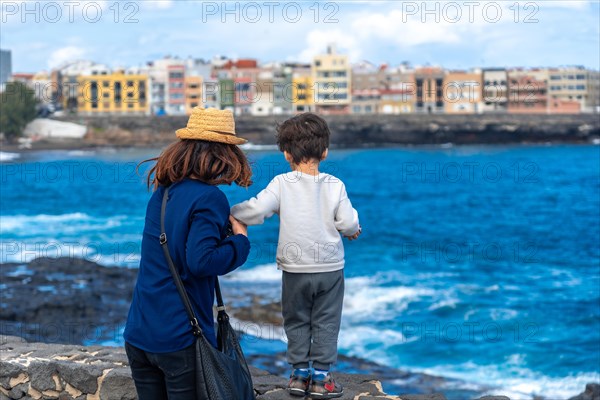Mother with her son looking at the sea on summer vacation, happy family enjoying
