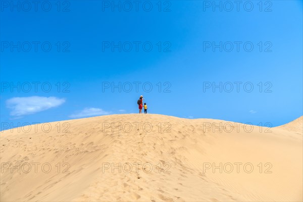 Mother and child walking in the dunes of Maspalomas in summer, Gran Canaria, Canary Islands