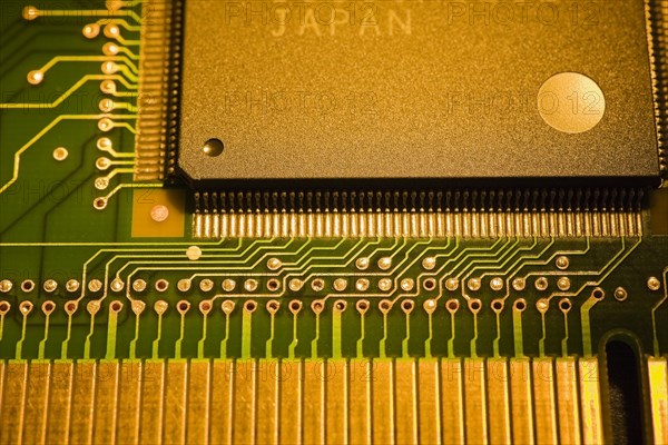 Close-up of golden yellow and green lighted electronic computer circuit board witrh memory chip, silver solder points and lines, Studio Composition, Quebec, Canada, North America