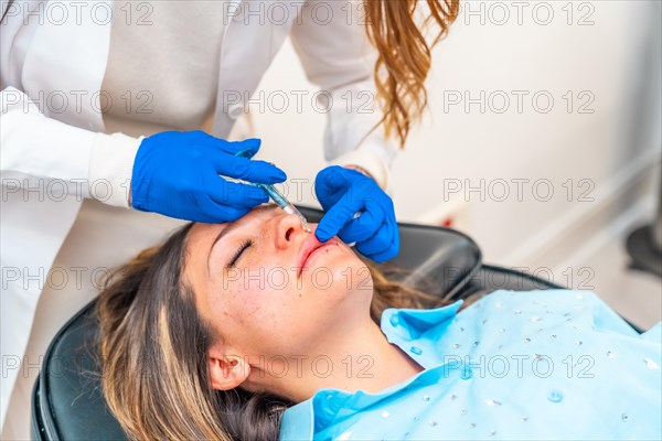 Cosmetologist making botox injection to the face of a caucasian adult woman in a clinic