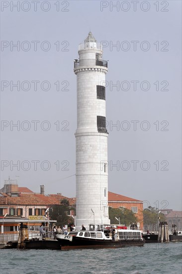 Island of Murano, A white lighthouse stands on the water with a small boat nearby, Venice, Veneto, Italy, Europe
