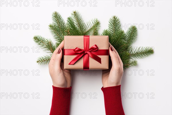 Top view of woman's hands holding christmas gift wrapped in craft paper and red ribbon. KI generiert, generiert, AI generated