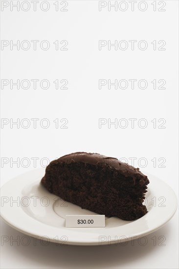 Close-up of slice of chocolate cake with rich creamy frosting and an expensive price tag of $30.00 dollars on white background, Studio Composition, Quebec, Canada, North America