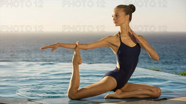 Elegant woman performing a yoga pose by the poolside with a view of the sea, AI generated