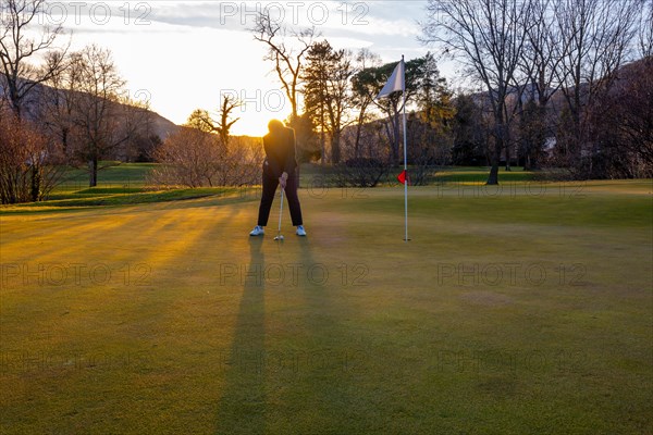 Female Golfer Concentration on the Putting Green on Golf Course in Sunset in Switzerland. | MR:yes Maria-CH-02-05-2023