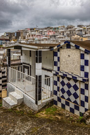 Famous cemetery, many mausoleums or large tombs decorated with tiles, often in black and white. Densely built buildings under a dramatic cloud cover Cimetiere de Morne-a-l'eau, Grand Terre, Guadeloupe, Caribbean, North America