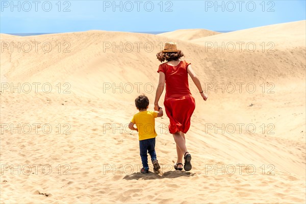 Mother and son on vacation walking in the dunes of Maspalomas, Gran Canaria, Canary Islands