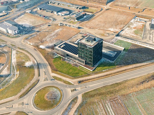 Drone shot of a modern office complex next to roundabout and surrounding fields in industrial area, sunrise, Nagold, Black Forest, Germany, Europe