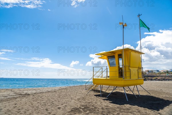 Yellow lifeguard tower in California with green flag