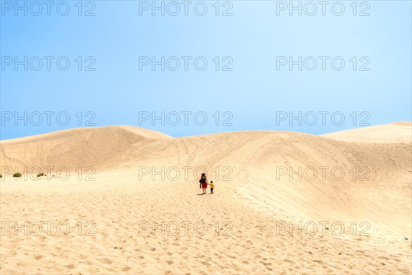 Father and son on vacation smiling in the dunes of Maspalomas, Gran Canaria, Canary Islands