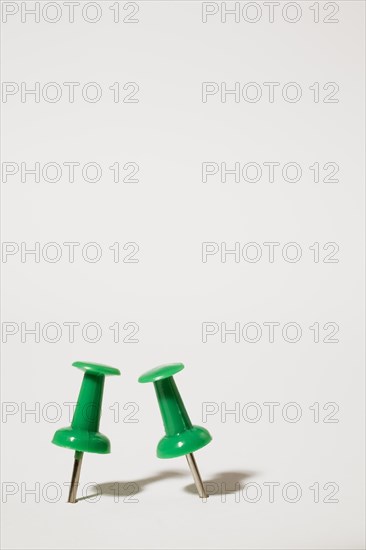 Close-up of two upright green plastic and chrome pushpins on white background, Studio Composition, Quebec, Canada, North America