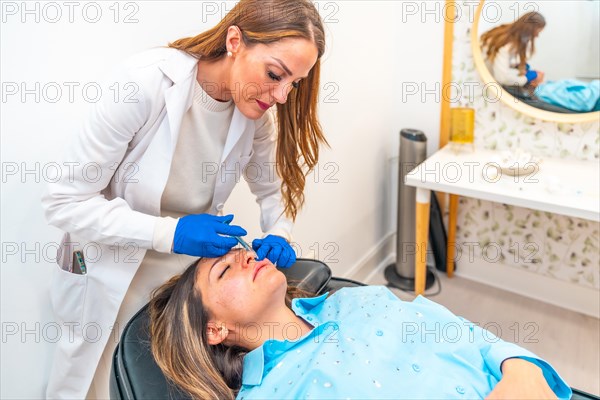 Woman and doctor during a rejuvenation treatment with hyaluronic acid injection in a clinic