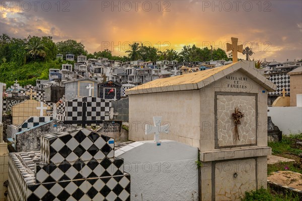 Famous cemetery, many mausoleums or large tombs decorated with tiles, often in black and white. Densely built buildings under a sunset Cimetiere de Morne-a-l'eau, Grand Terre, Guadeloupe, Caribbean, North America