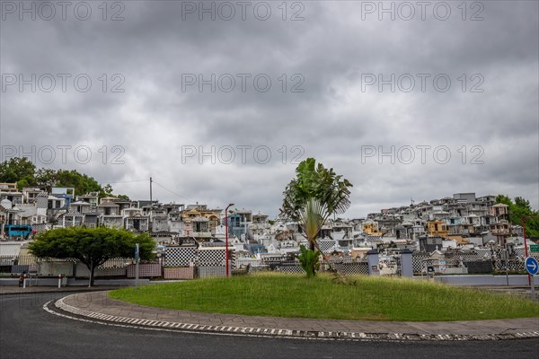 Famous cemetery, many mausoleums or large tombs decorated with tiles, often in black and white. Densely built buildings under a dramatic cloud cover Cimetiere de Morne-a-l'eau, Grand Terre, Guadeloupe, Caribbean, North America