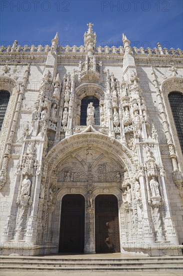 Jeronimos Monastery facade with arched front entrance door decorated with carved sculptures, Lisbon, Portugal, Europe