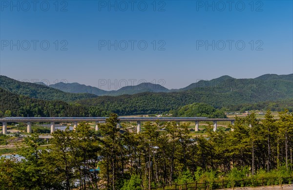 High speed train speeding across concrete railroad bridge in rural countryside in South Korea