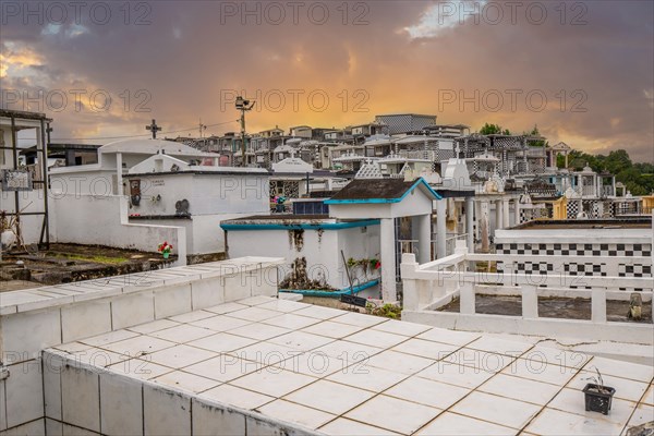 Famous cemetery, many mausoleums or large tombs decorated with tiles, often in black and white. Densely built buildings under a sunset Cimetiere de Morne-a-l'eau, Grand Terre, Guadeloupe, Caribbean, North America