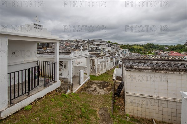 Famous cemetery, many mausoleums or large tombs decorated with tiles, often in black and white. Densely built buildings under a dramatic cloud cover Cimetiere de Morne-a-l'eau, Grand Terre, Guadeloupe, Caribbean, North America