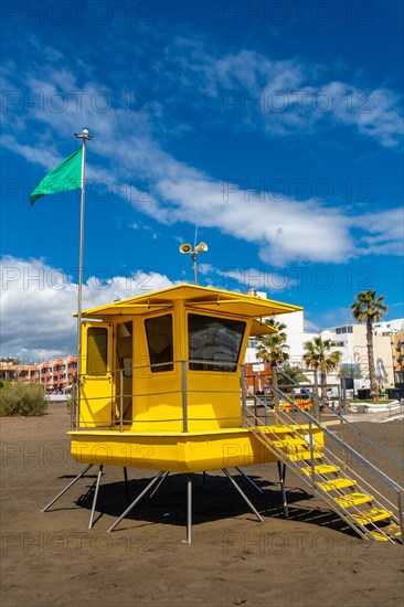 Yellow lifeguard tower in California with green flag