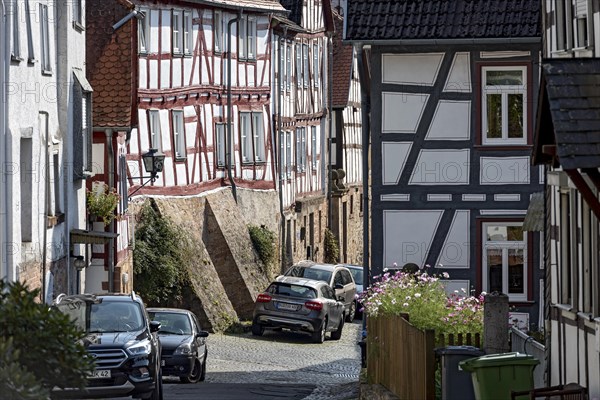 Old half-timbered houses on a narrow alley, parked cars, Untergasse, old town, Ortenberg, Vogelsberg, Wetterau, Hesse, Germany, Europe