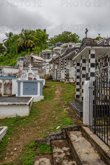 Famous cemetery, many mausoleums or large tombs decorated with tiles, often in black and white. Densely built buildings under a dramatic cloud cover Cimetiere de Morne-a-l'eau, Grand Terre, Guadeloupe, Caribbean, North America