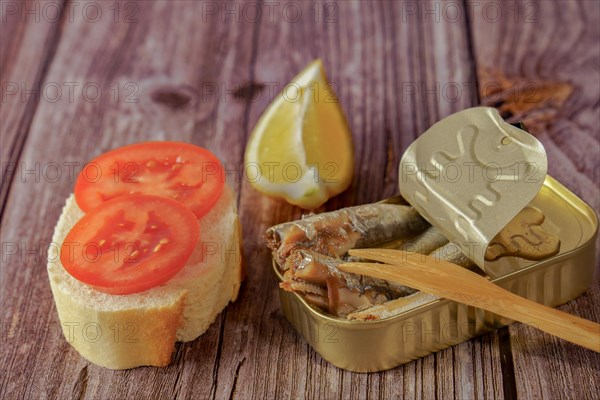 Can of tasty sprats with a slice of bread with tomato and lemon