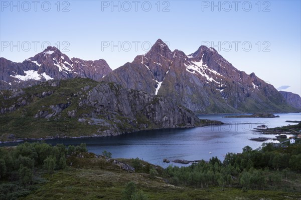 Mountain landscape on the Lofoten Islands. View over the Maervollspollen fjord to the mountains. At night at the time of the midnight sun in good weather, blue sky. Vestvagoya, Lofoten, Norway, Europe