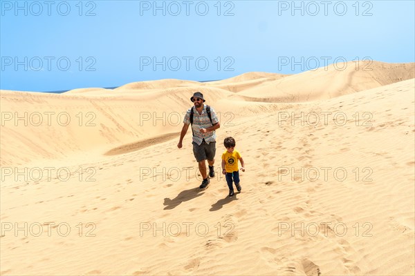 Father and son on vacation laughing running in the dunes of Maspalomas, Gran Canaria, Canary Islands