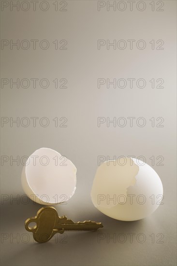 Close-up of antique brass key and two white cracked opened chicken egg shells on grey background, Studio Composition, Quebec, Canada, North America