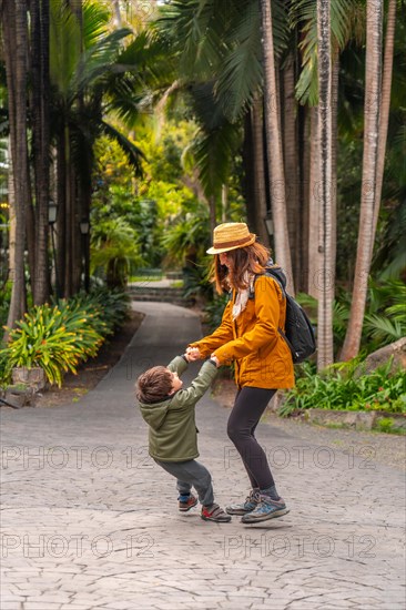 A woman and a child are playing in a park. The woman is holding the child's hand and they are both smiling