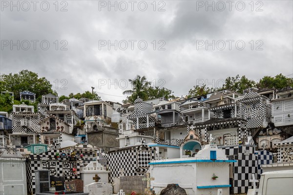 Famous cemetery, many mausoleums or large tombs decorated with tiles, often in black and white. Densely built buildings under a dramatic cloud cover Cimetiere de Morne-a-l'eau, Grand Terre, Guadeloupe, Caribbean, North America