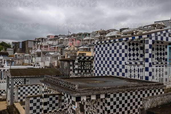 Famous cemetery, many mausoleums or large tombs decorated with tiles, often in black and white. Densely built buildings under a dramatic cloud cover Cimetiere de Morne-a-l'eau, Grand Terre, Guadeloupe, Caribbean, North America