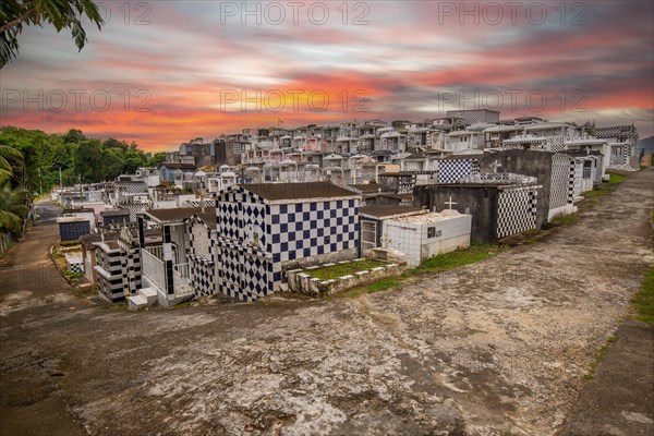 Famous cemetery, many mausoleums or large tombs decorated with tiles, often in black and white. Densely built buildings under a sunset Cimetiere de Morne-a-l'eau, Grand Terre, Guadeloupe, Caribbean, North America