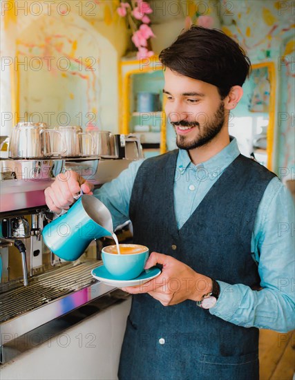 A smiling bearded barista pouring milk into a coffee cup, standing by an espresso machine inside a cafe, Vertical aspect ratio, AI generated
