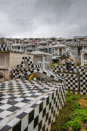 Famous cemetery, many mausoleums or large tombs decorated with tiles, often in black and white. Densely built buildings under a dramatic cloud cover Cimetiere de Morne-a-l'eau, Grand Terre, Guadeloupe, Caribbean, North America