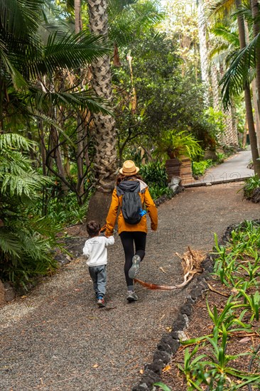 A mother and child enjoying and walking in a botanical garden. Family vacation concept