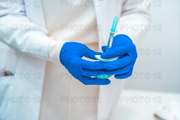 Doctor with protective gloves and uniform holding an hyaluronic acid injection in the clinic