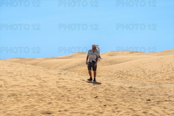 Portrait of male tourist in summer walking in the dunes of Maspalomas, Gran Canaria, Canary Islands