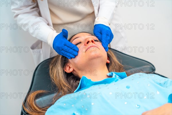 Aesthetic female doctor applying numbing cream on the face of a woman before injecting hyaluronic acid during a beauty treatment in the clinic